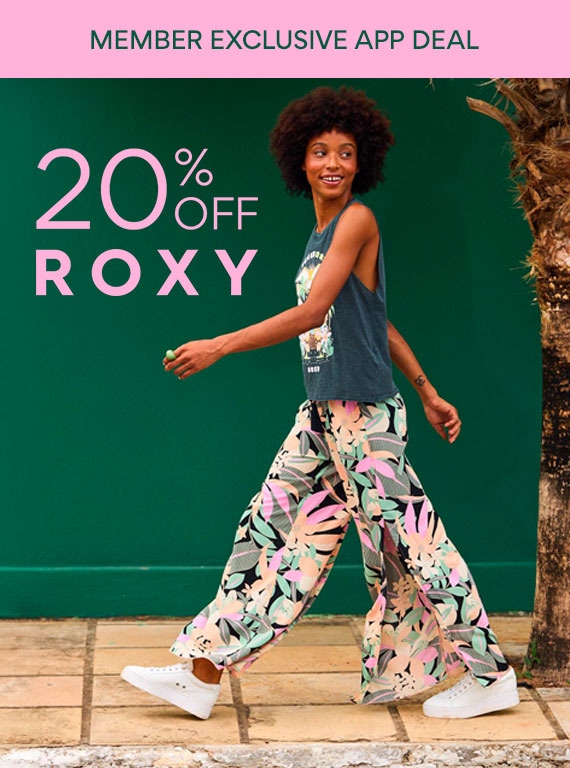 rewards member exclusive app deal: 20% off roxy. woman in floral pants walking wearing white roxy sneakers on sale
